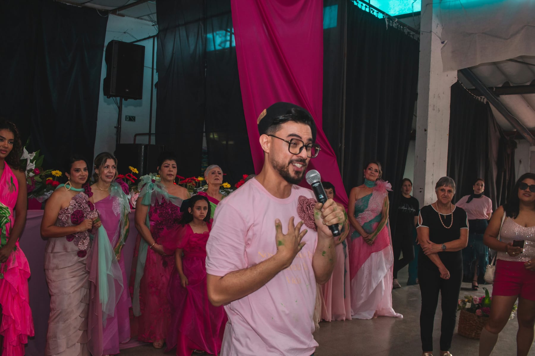 William Malagres fala ao microfone diante das participantes do desfile