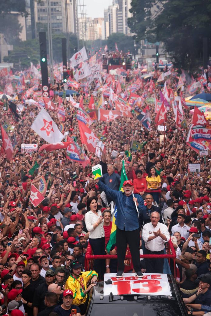 Lula segura a Constituição e a bandeira do Brasil em ato na Avenida Paulista